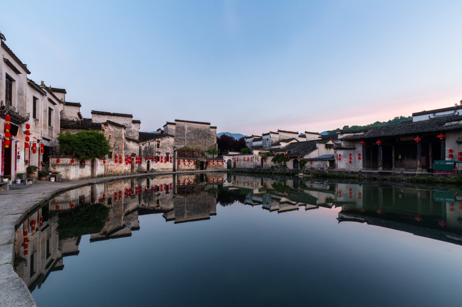 Hongcun's lantern-lit Huizhou houses mirrored in the village pond at dusk