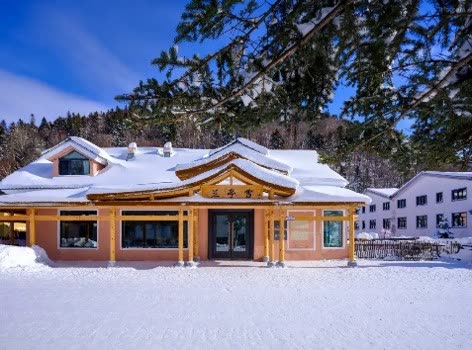 Snow-covered timber facade of Lanting Snow Hotel by day