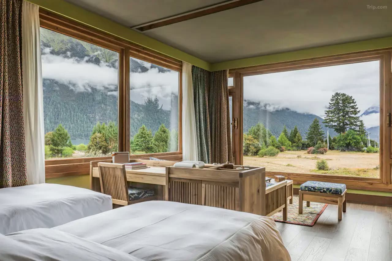 Twin room with floor-to-ceiling windows framing the lake and mountains at Songtsam Basong Tso Lodge