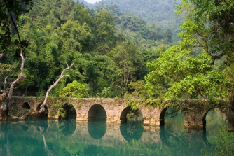 The Seven Small Arches stone bridge over emerald water at Libo