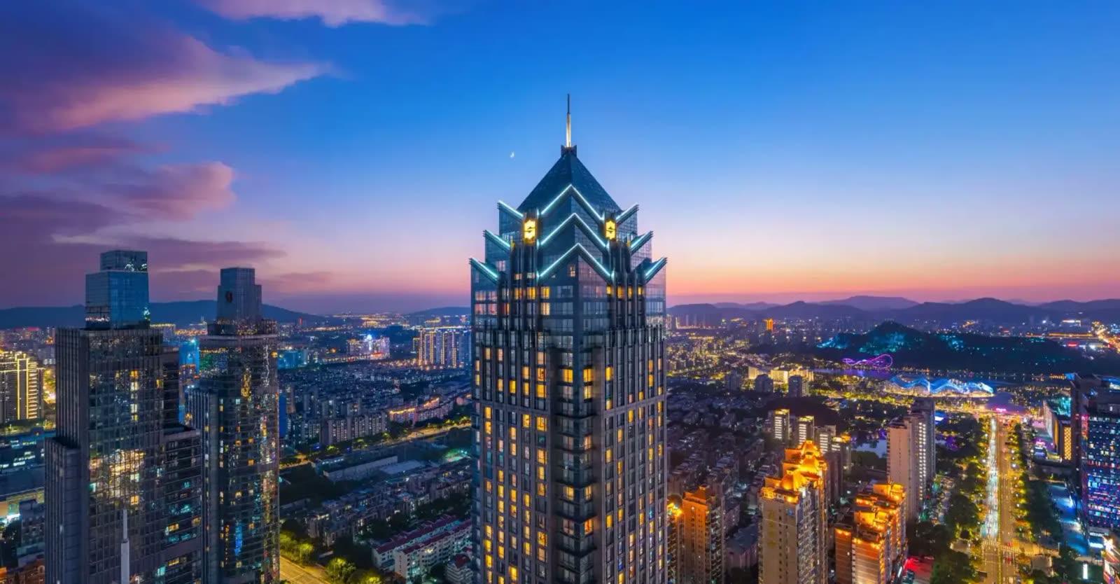 Illuminated Shangri-La Suzhou tower above the city at dusk