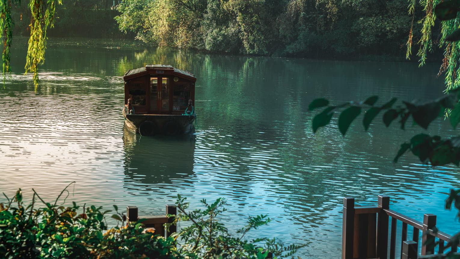 Traditional wooden boat on the willow-lined water beside Four Seasons Hotel Hangzhou