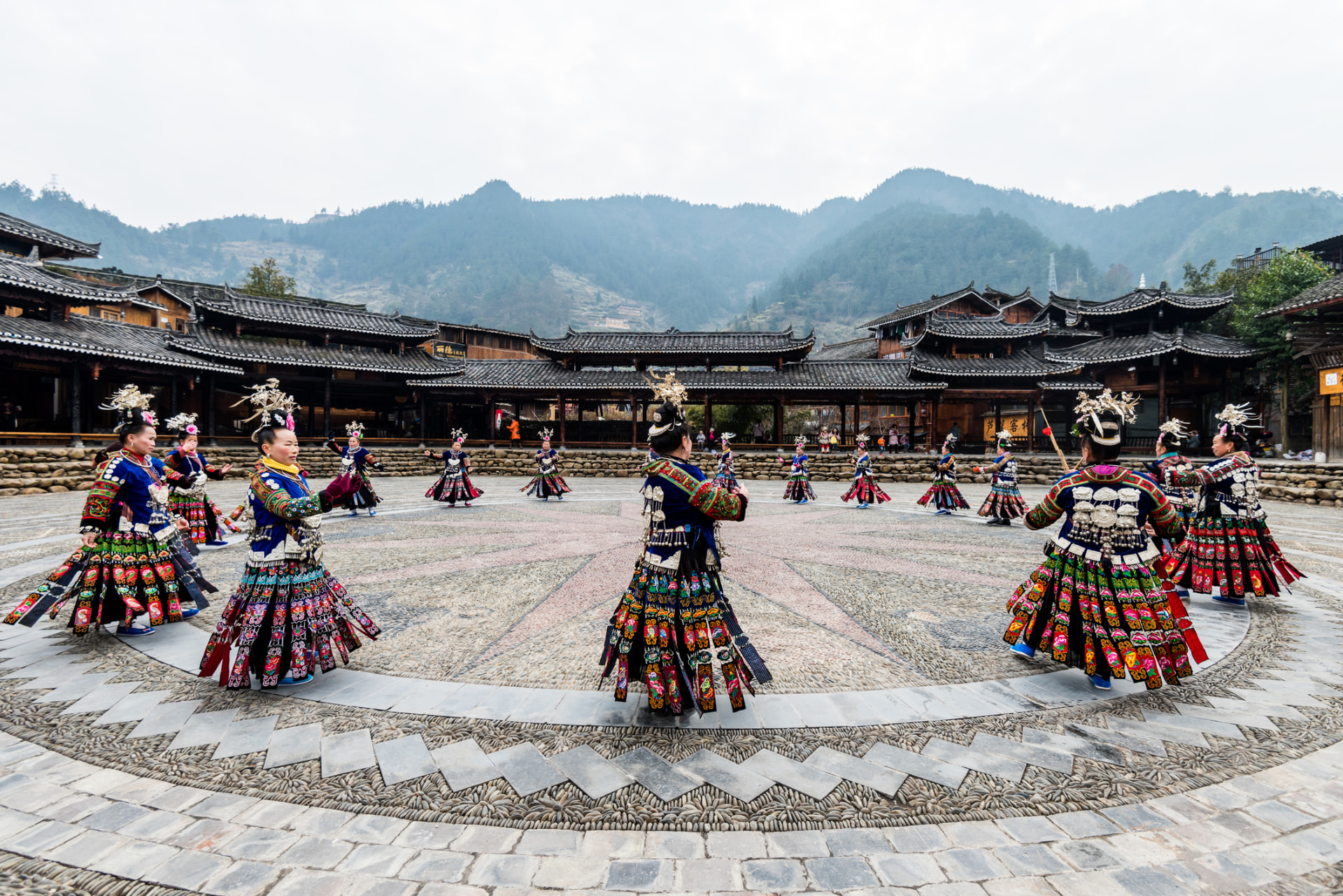 Miao women in full festival dress dancing in the village square at Xijiang