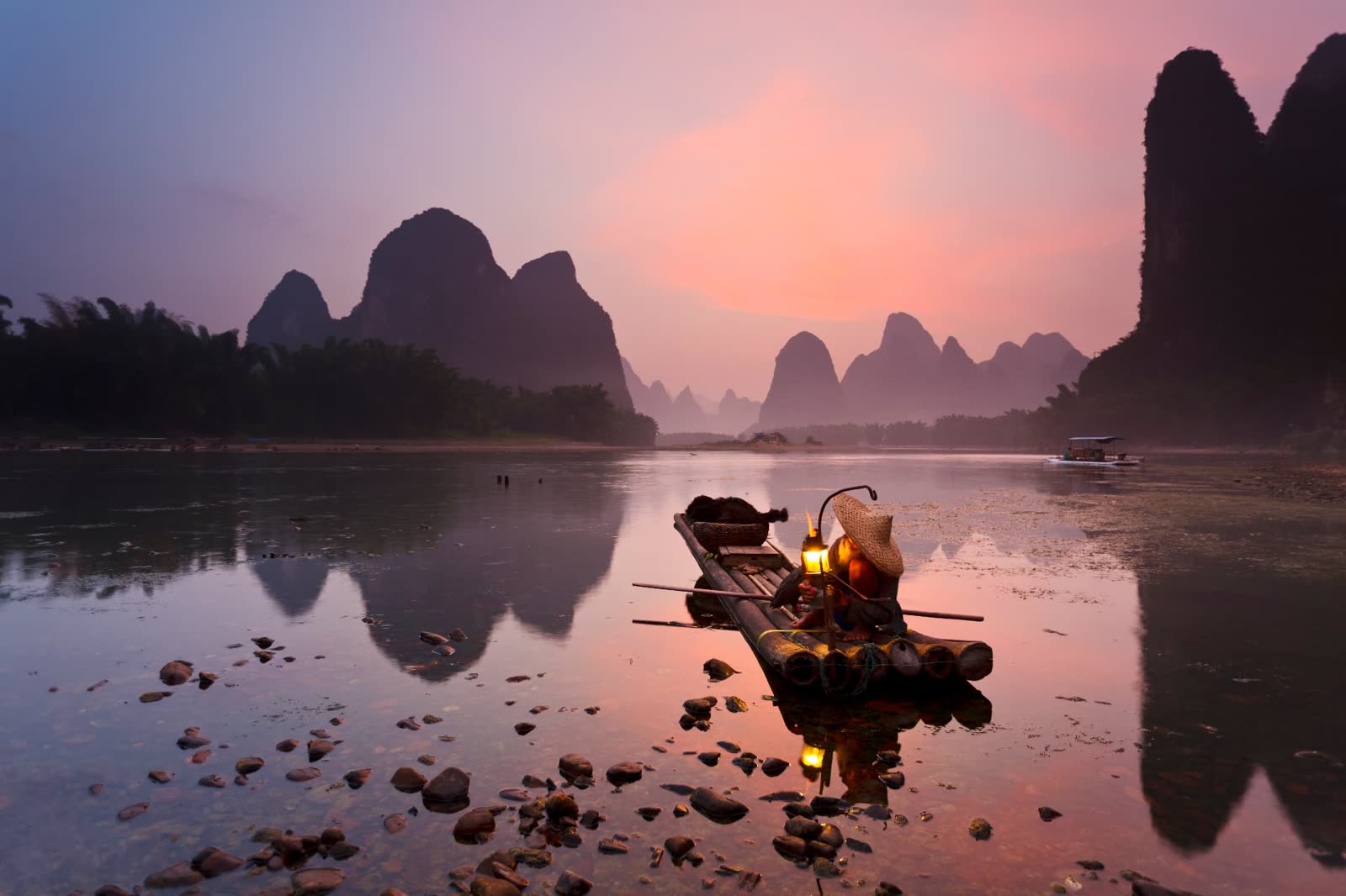 Bamboo raft with cormorant fishing lanterns on the Li River at dusk