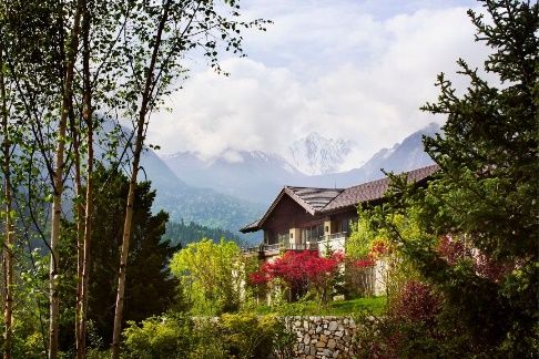 Rissai Valley, a Ritz-Carlton Reserve, seen through trees with snow peaks beyond