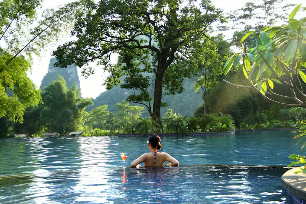 Swimming pool at Yangshuo Resort framed by trees and karst peaks