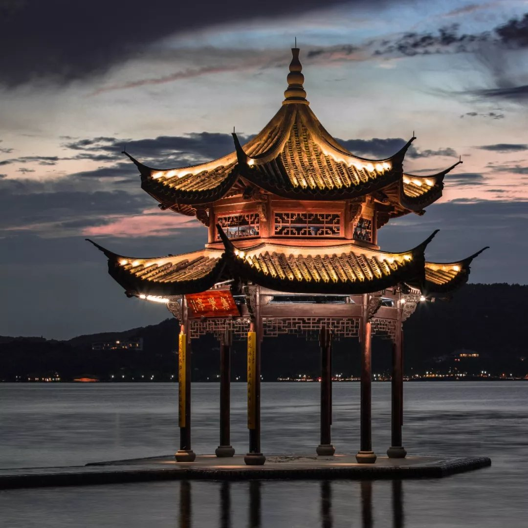 A gilded pavilion lit at dusk on the shores of West Lake, Hangzhou